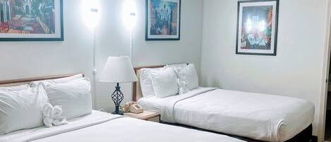 Habitación de hotel con dos camas individuales, una mesita de noche con lámpara y teléfono.