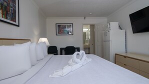 Una habitación de hotel con una cama grande, un escritorio, una silla, un televisor y un microondas.