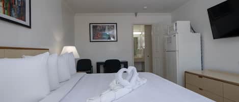 Une chambre d’hôtel avec un grand lit, un bureau, une chaise, une télévision et un four à micro-ondes.