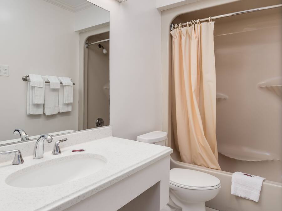 Un baño moderno con lavamanos doble, inodoro y ducha con cortina color beige.