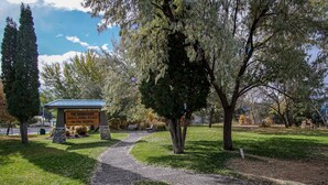 A park with a sign reading "The Mountains Shall Bring Peace to the People," a paved path, and a building with a blue roof. - Gables Motel (Radium Hot Springs)