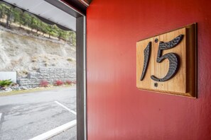 Une plaque en bois portant le numéro 15, fixée sur un mur rouge.
