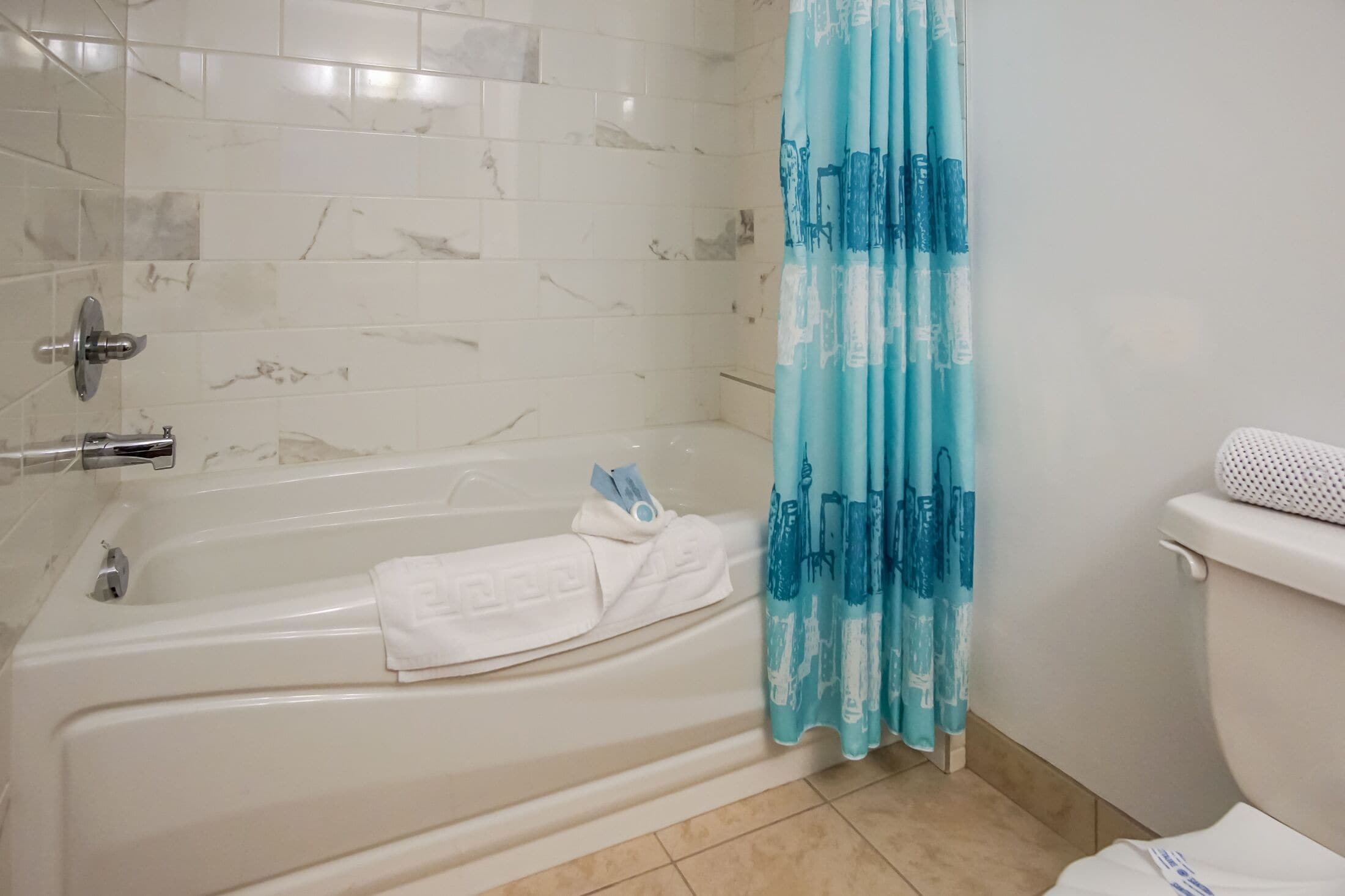 A bathroom with a bathtub, a toilet, and a shower curtain.
