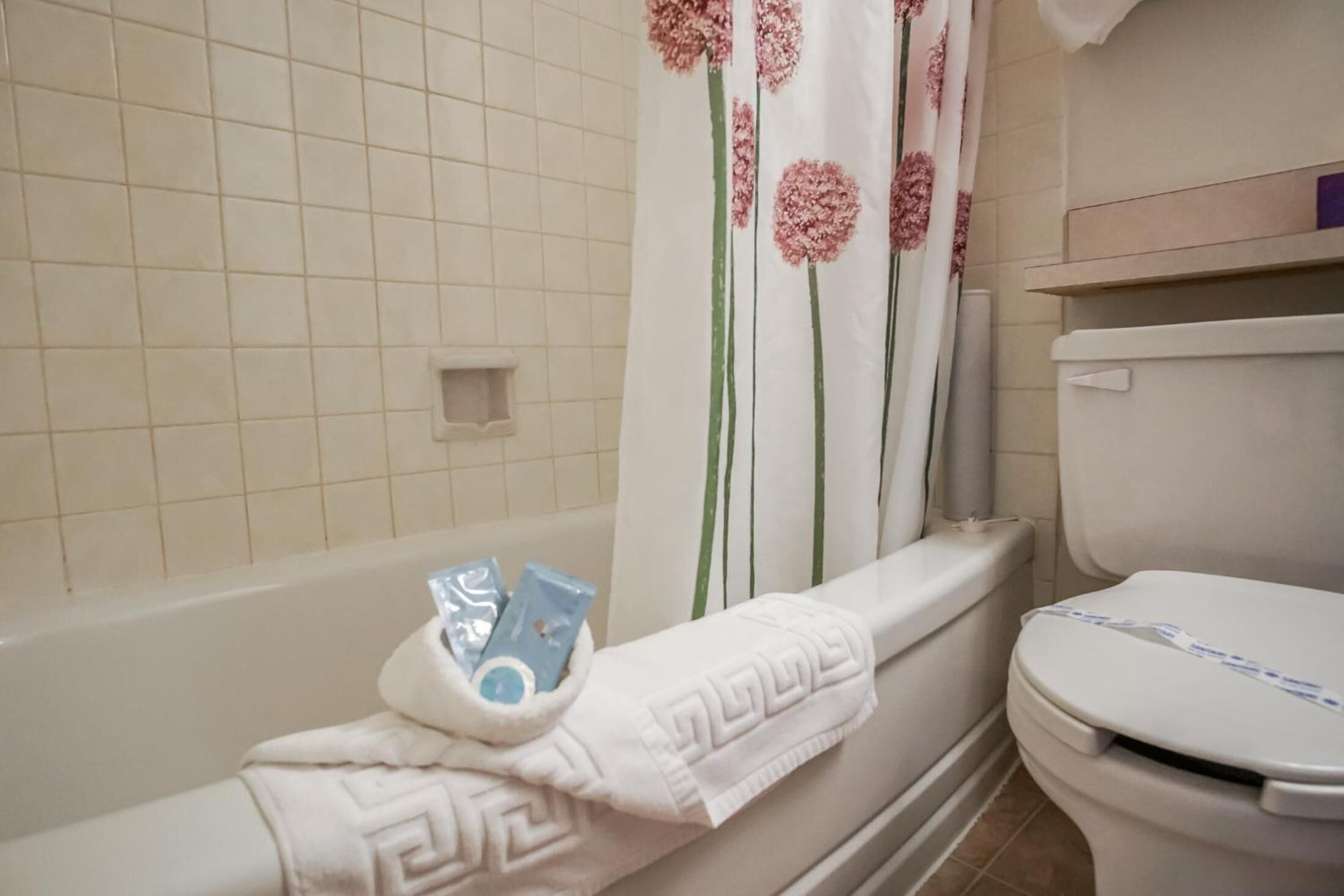 A bathroom with a bathtub, toilet, and shower curtain.