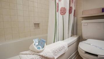 Un baño con bañera, inodoro y cortina de ducha.