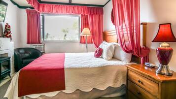 Ein ordentlich eingerichtetes Schlafzimmer mit Bett, Nachttischlampen, einem Schminktisch und einem Fenster mit Vorhängen.