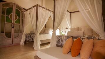 A bedroom with a four-poster bed, a canopy bed, and a separate bed with a canopy.