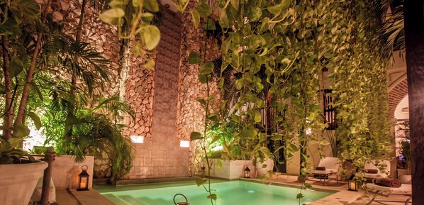 An indoor swimming pool with stone walls and lush greenery. - Casa De Alba Hotel Boutique (Cartagena)