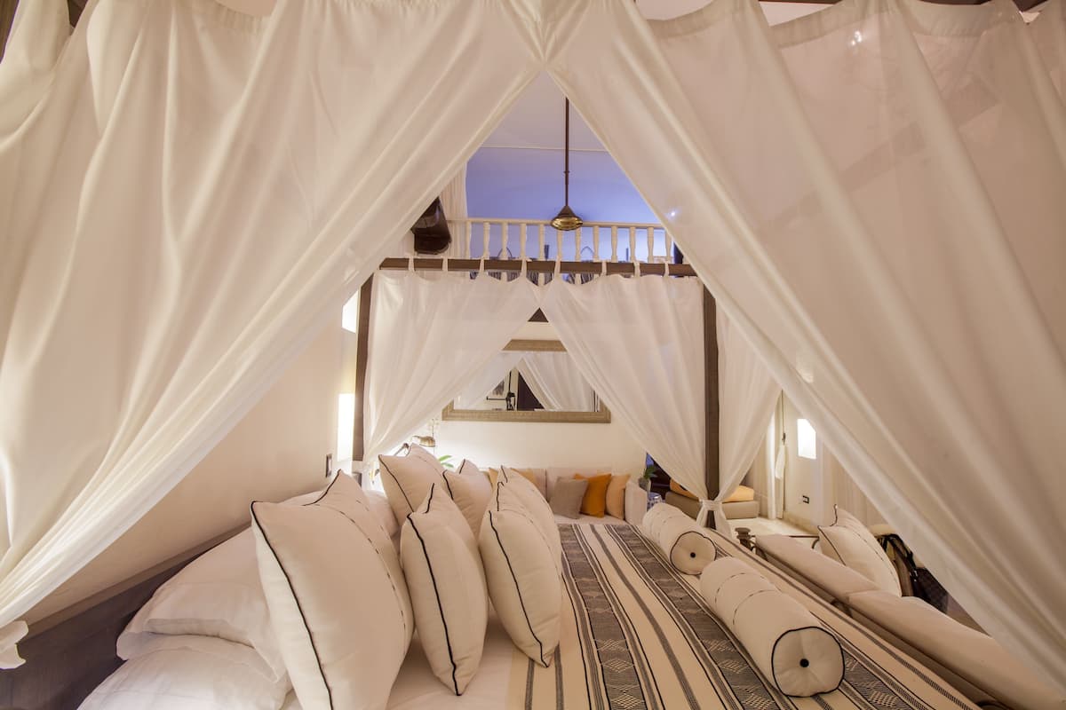 Un dormitorio tipo tienda con cama con dosel, almohadas y una lámpara colgante.