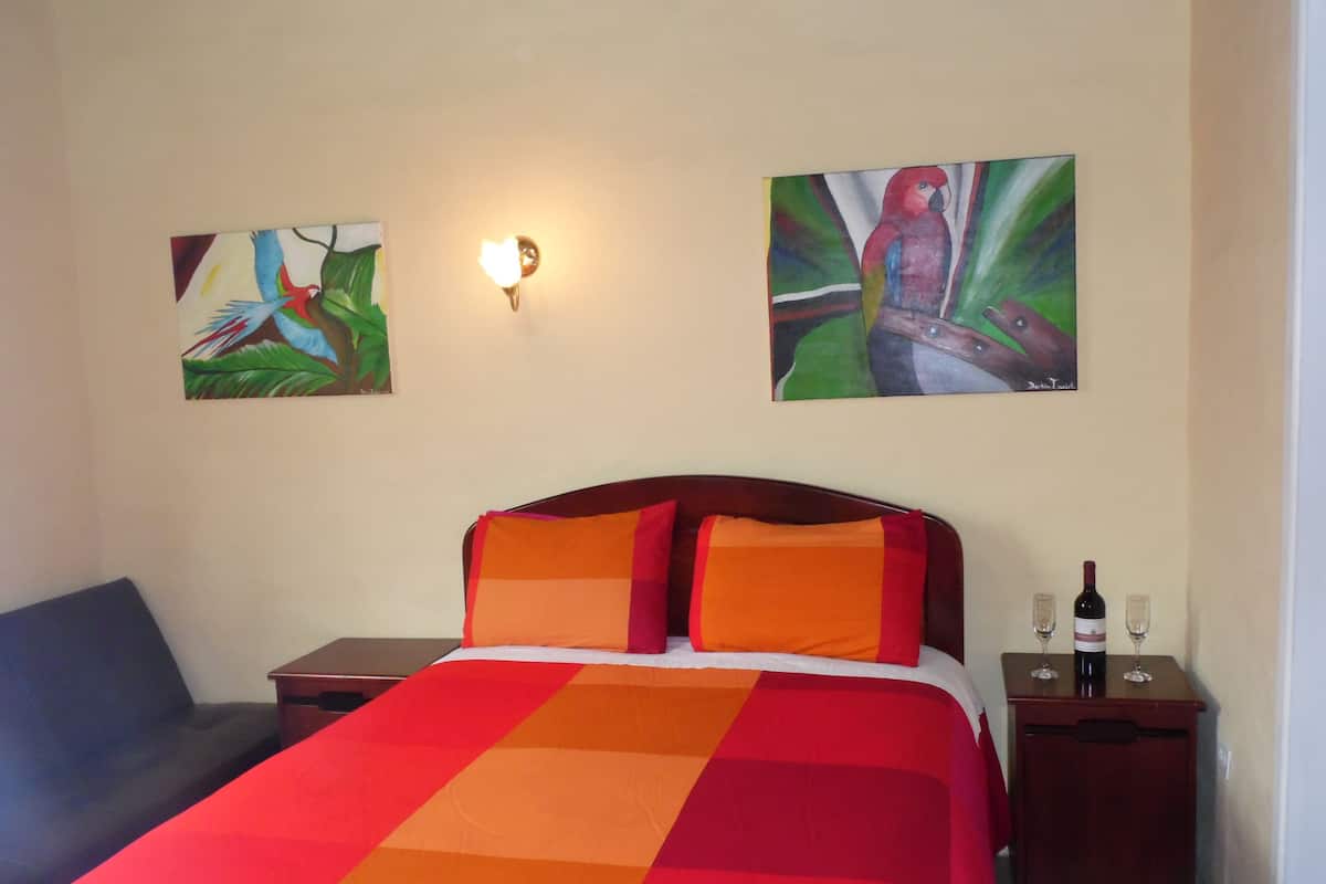 A hotel room with a large bed, two nightstands, a lamp, and two paintings on the wall.