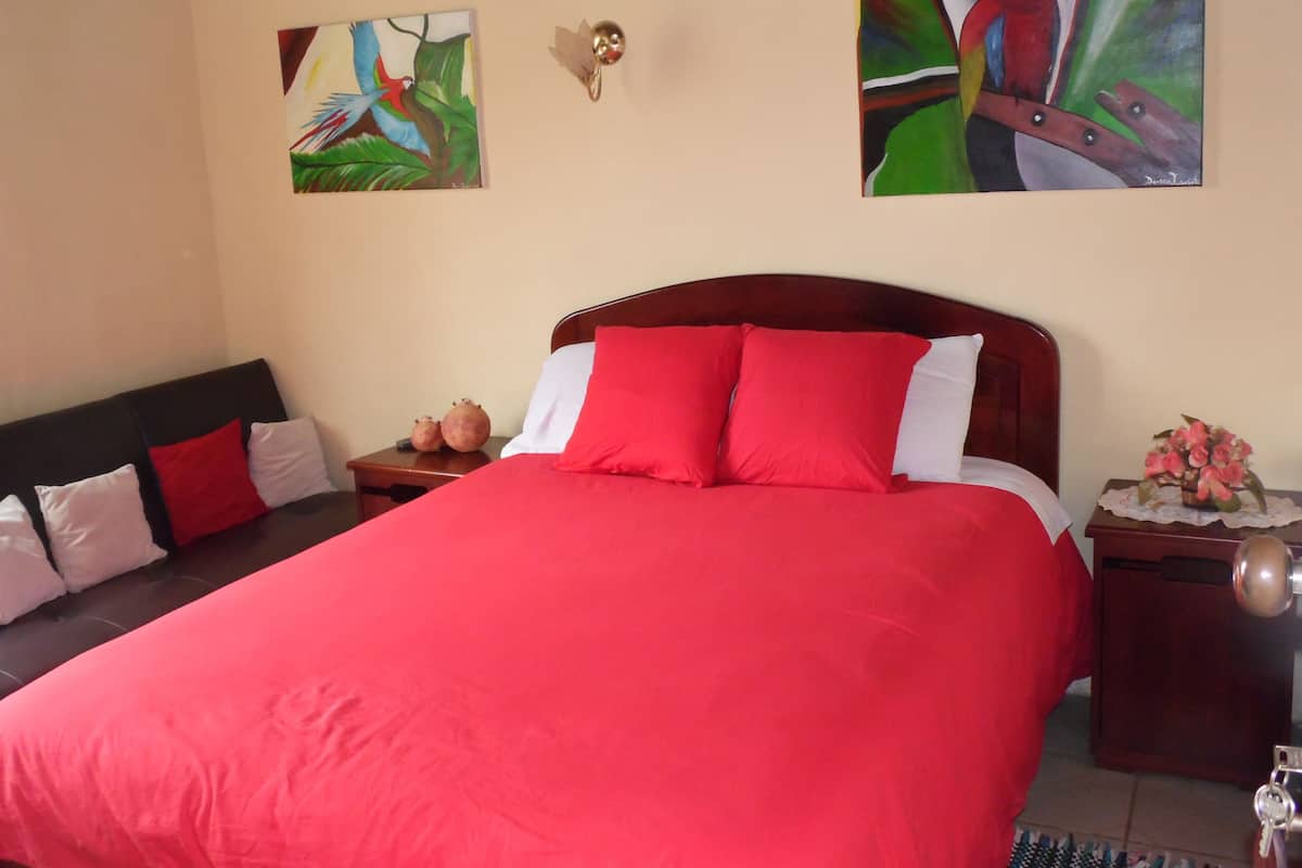 A bed with red bedding, a wooden headboard, and two nightstands with decorative items.