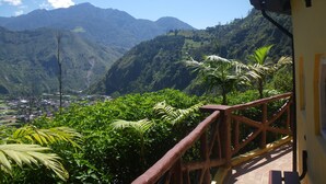 Un balcon offrant une vue sur de luxuriantes montagnes verdoyantes et une ville située au loin.
