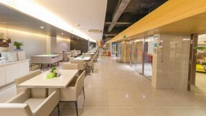 A modern indoor space with long tables and benches, a clear pathway, and glass storefronts. - Jinjiang Inn (Beijing Wangfujing) (Beijing)