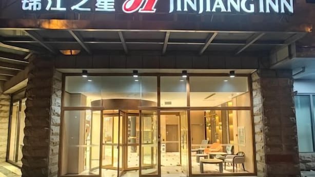 The exterior of Jinjiang Inn with a stone facade, large glass entrance, and a well-lit interior visible through the doors. - Jinjiang Inn (Beijing Wangfujing) (Beijing)