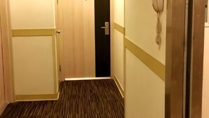 A narrow hallway with wooden flooring, a door on the left, and a wall-mounted telephone on the right. - Jinjiang Inn (Beijing Wangfujing) (Beijing)