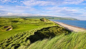 A coastal landscape with a golf course and a beach.