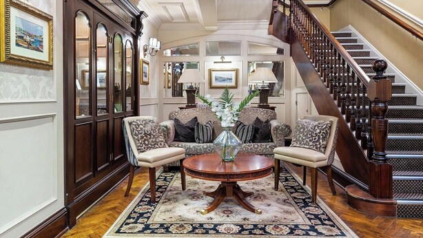 A grand lobby with a staircase, wooden furniture, and a chandelier.