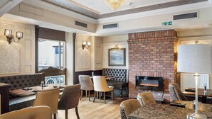 A dining area with a brick fireplace, leather seating, and a chandelier.