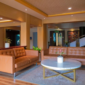 A lobby with leather sofas, a marble coffee table, and a staircase.