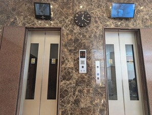 An elevator with a digital display, two doors, and a marble wall with two screens above. - Toyoko Inn Sasebo Ekimae (Sasebo)