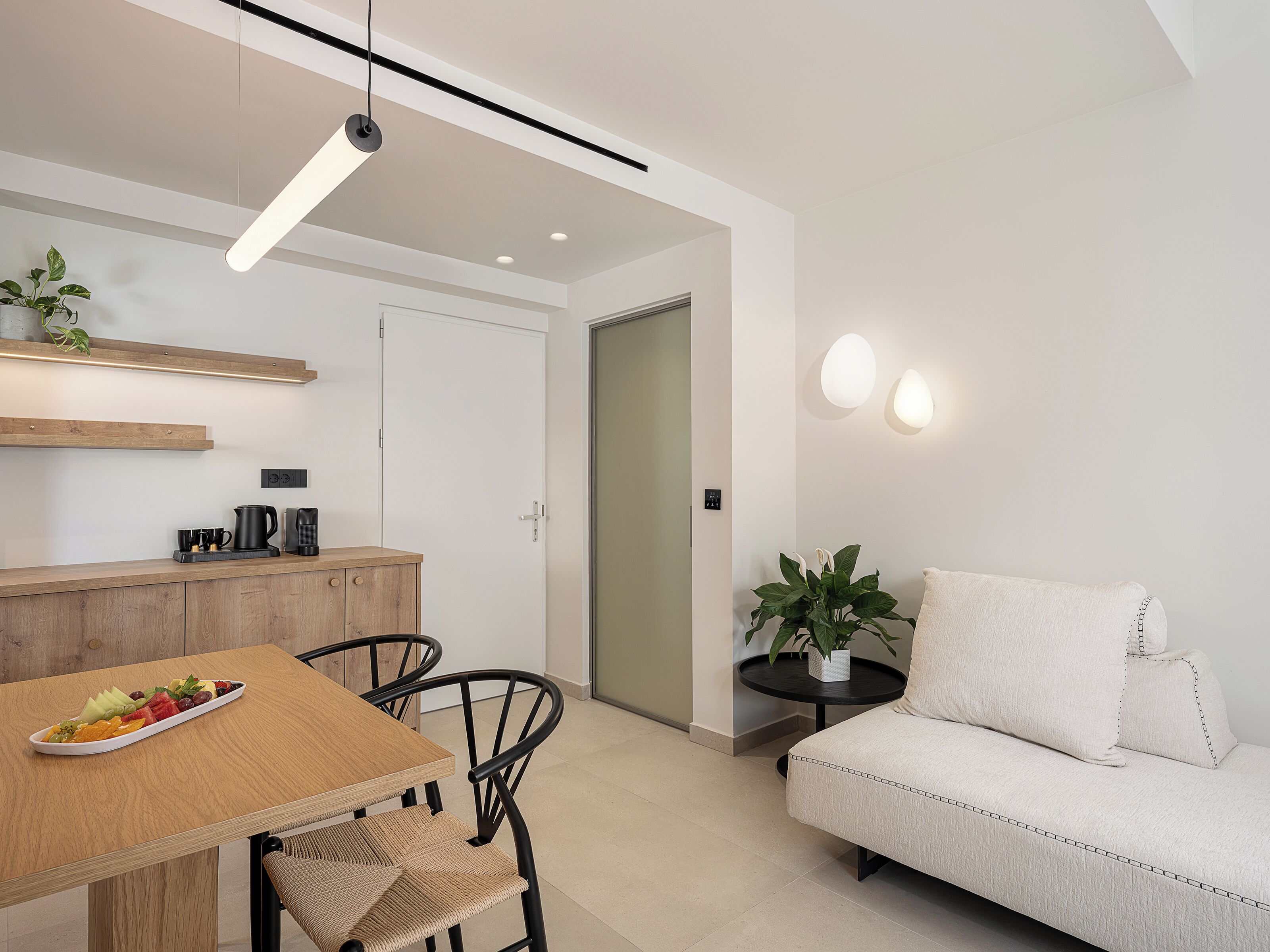 Una sala de estar moderna con un sofá, una mesa de comedor con sillas, una cafetera y una planta en maceta.