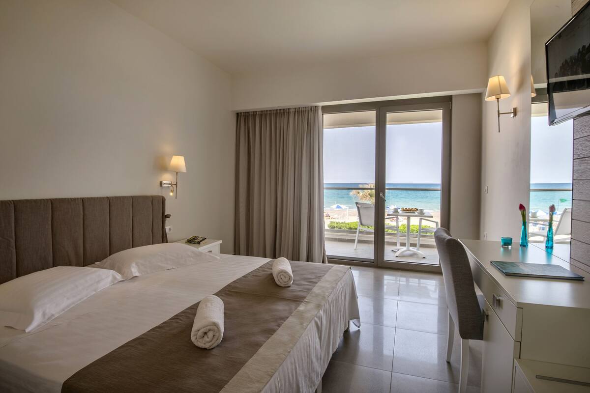 A hotel room with a bed, a desk, and a view of the ocean.