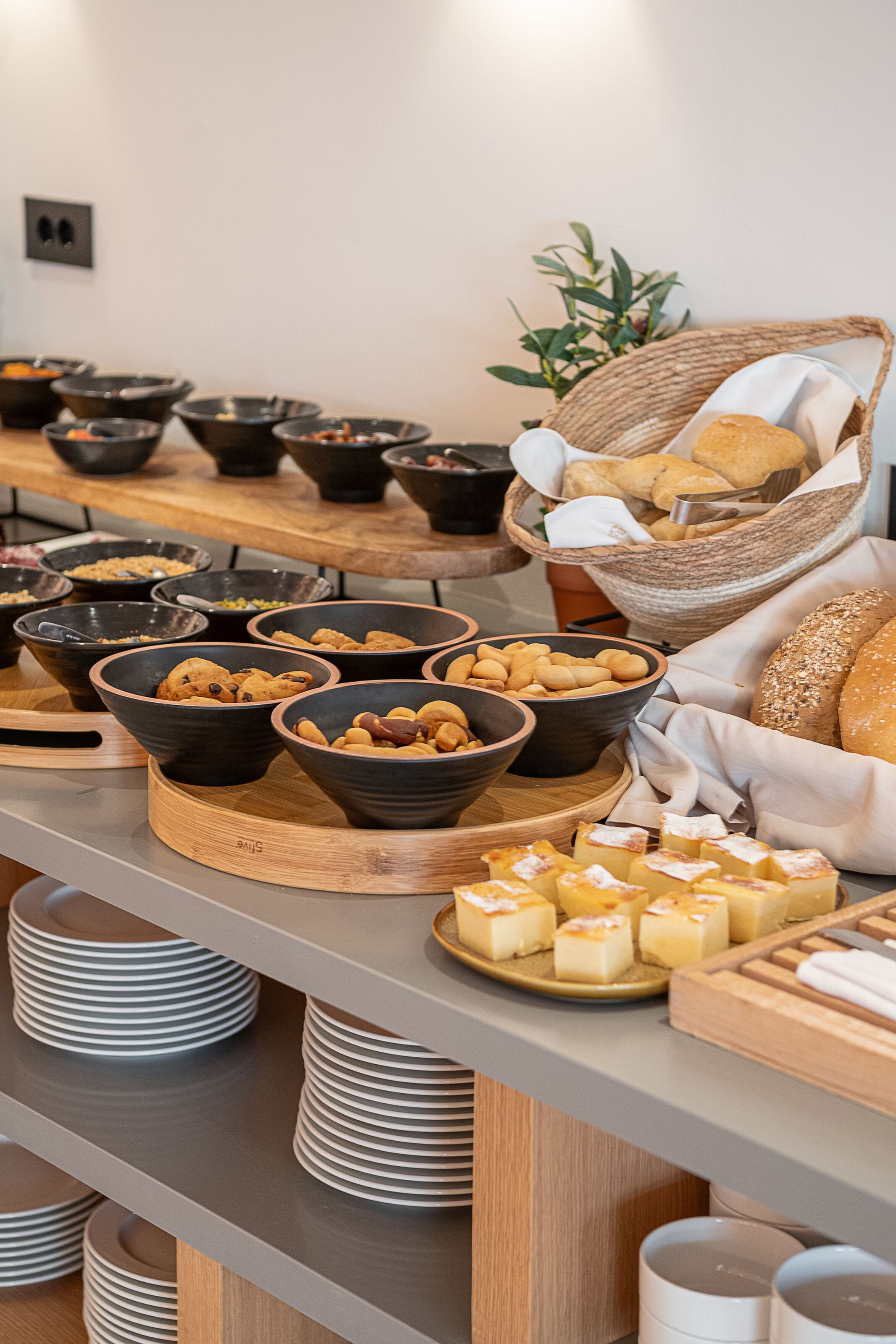 A buffet with various food items and bowls on a wooden table.