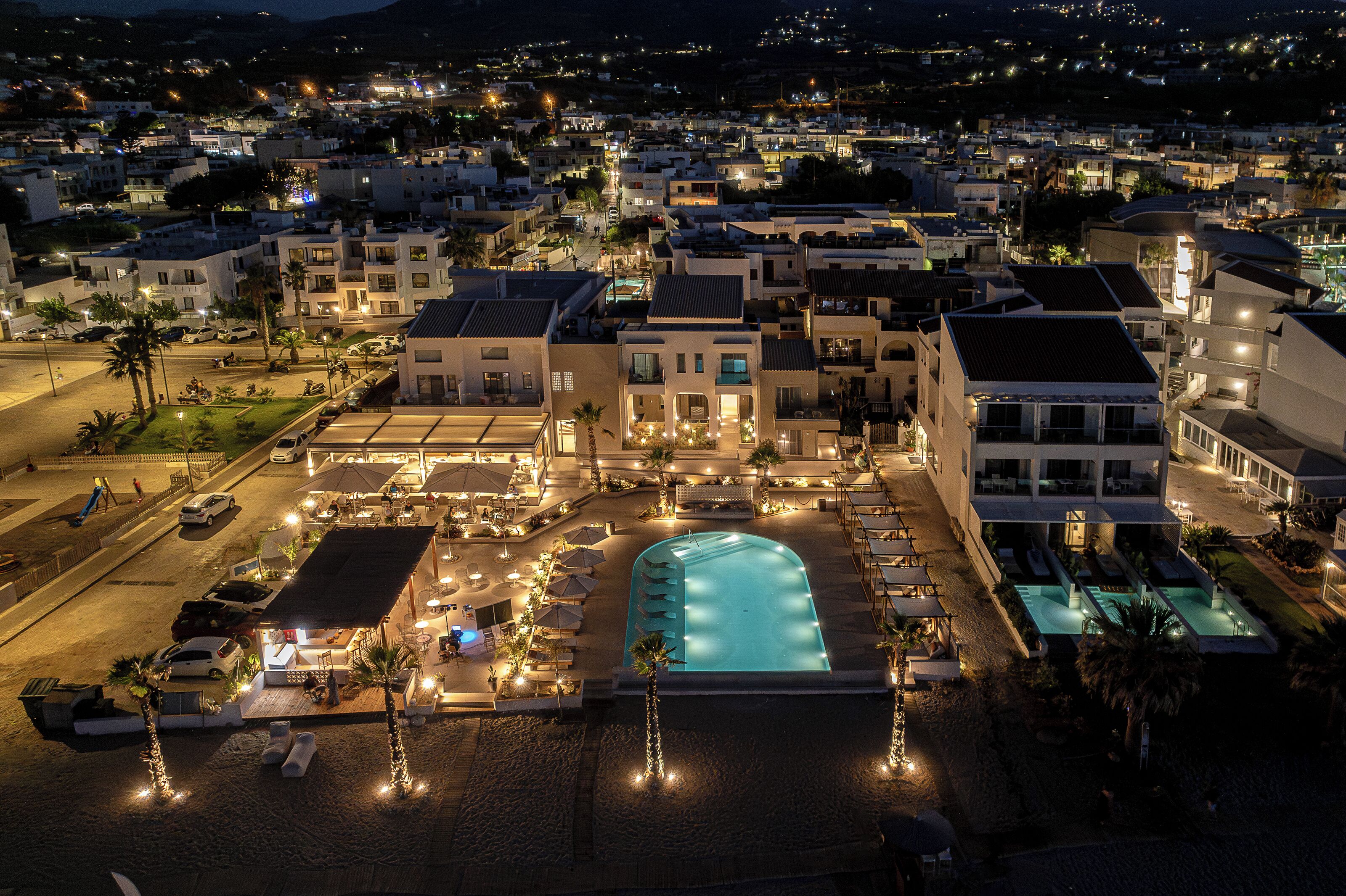 Un resort con piscina, mobiliario exterior y vistas del pueblo circundante.