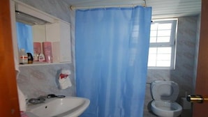 A bathroom with a sink, toilet, and a shower curtain. - Sevi Sun Studios and Apartments (Kos)