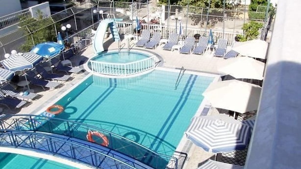 A pool area with lounge chairs and umbrellas, a lifeguard stand, and a small bridge. - Sevi Sun Studios and Apartments (Kos)