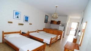 A room with three wooden beds, a kitchenette, and a dining area. - Sevi Sun Studios and Apartments (Kos)