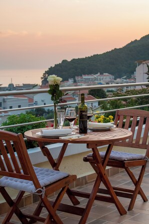A table set for two with a bottle of wine, glasses, and a vase with flowers.
