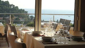 Ein Esstisch, gedeckt für eine Mahlzeit, mit Blick auf das Meer.