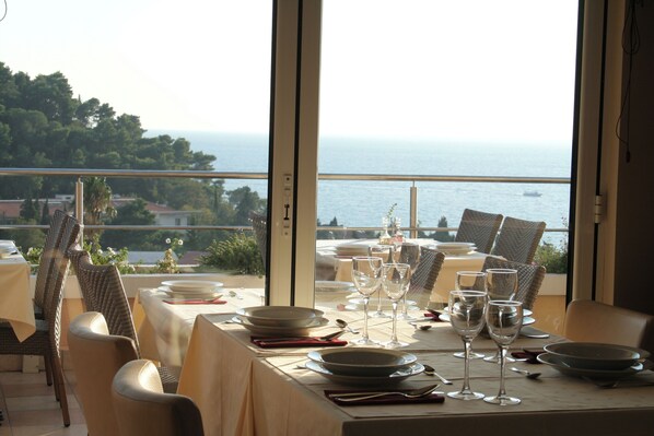 A dining table set for a meal with a view of the sea.