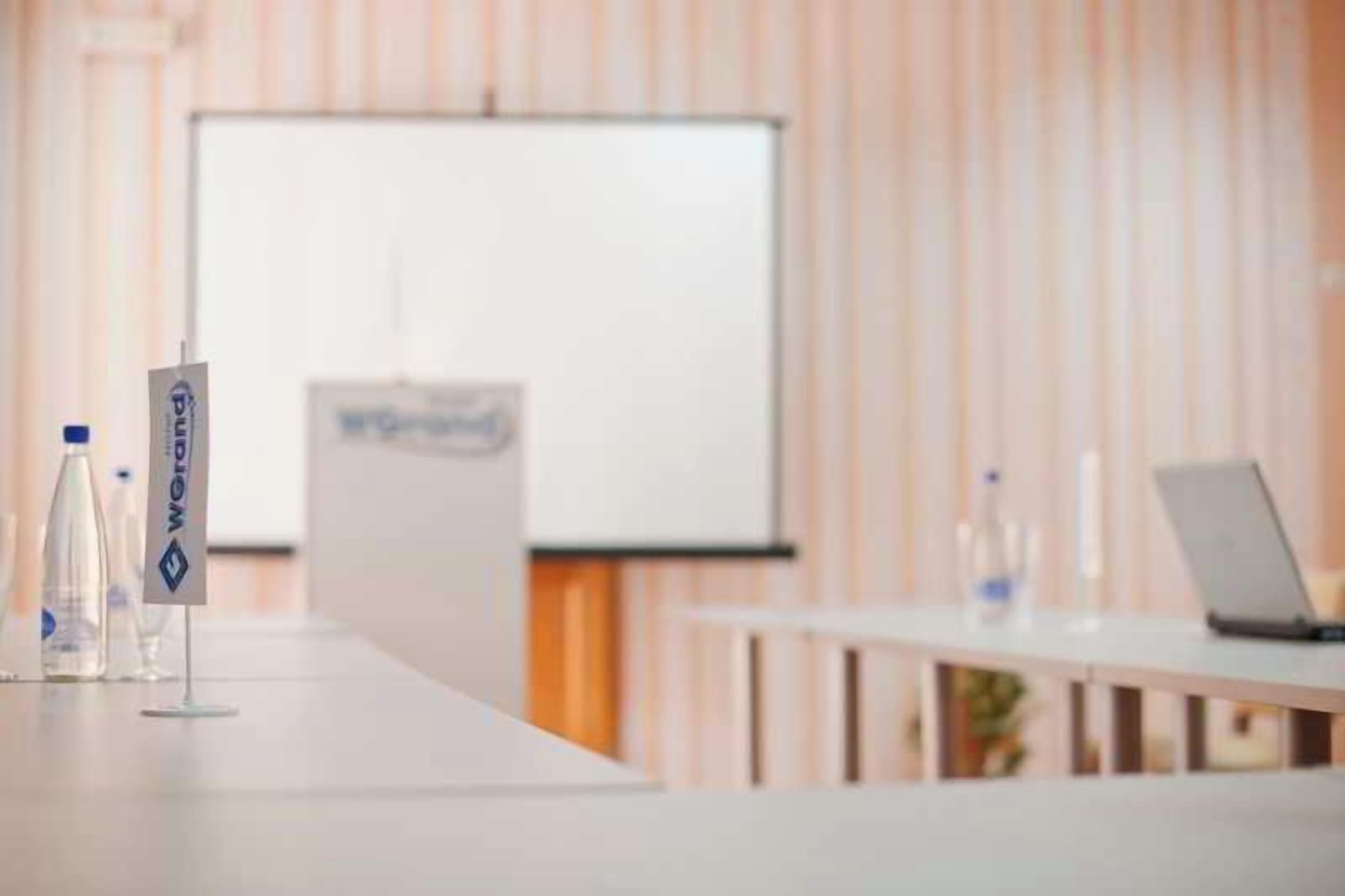 Una sala de conferencias con una pizarra, una computadora portátil y botellas de agua sobre una mesa.