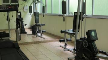 A gym with various exercise equipment, including a treadmill, weight machines, and a stationary bike.