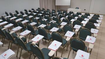 Une salle de conférence avec des rangées de chaises et de tables, chacune étant munie d’une plaque nominative.