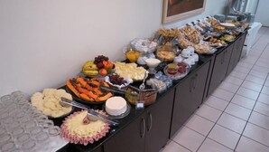 Een buffet met diverse etenswaren, zoals fruit, kazen en gebak.