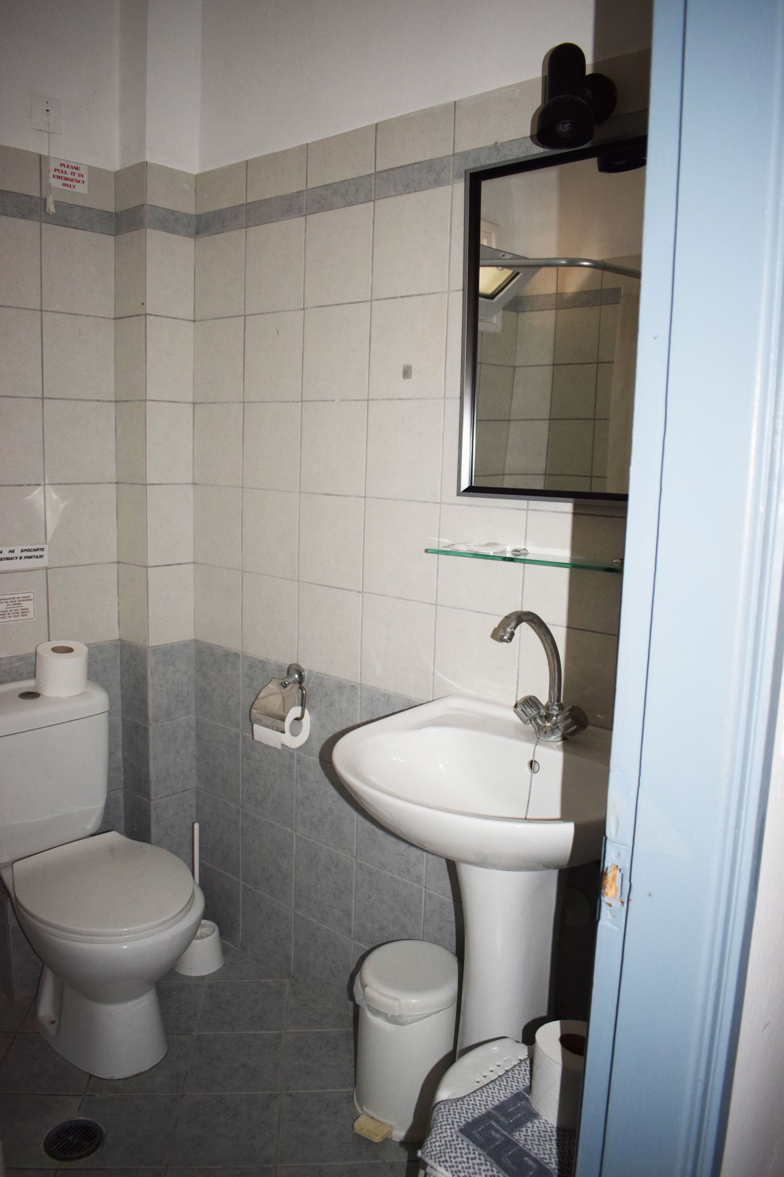 A bathroom with a toilet, bidet, sink, and glass shelf.