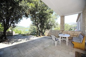 An outdoor patio with a stone floor, a round table, two chairs, and a striped sofa. - Villa Marijeta (Dubrovnik)