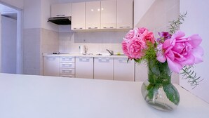 A modern kitchen with white cabinets, a stainless steel sink, and a vase of pink flowers on the counter. - Villa Marijeta (Dubrovnik)