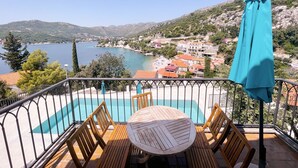 A balcony with a pool, wooden chairs, and a table. - Villa Marijeta (Dubrovnik)