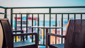 Een balkon met rieten stoelen en een kleine ronde tafel, met uitzicht op een stadsgezicht.