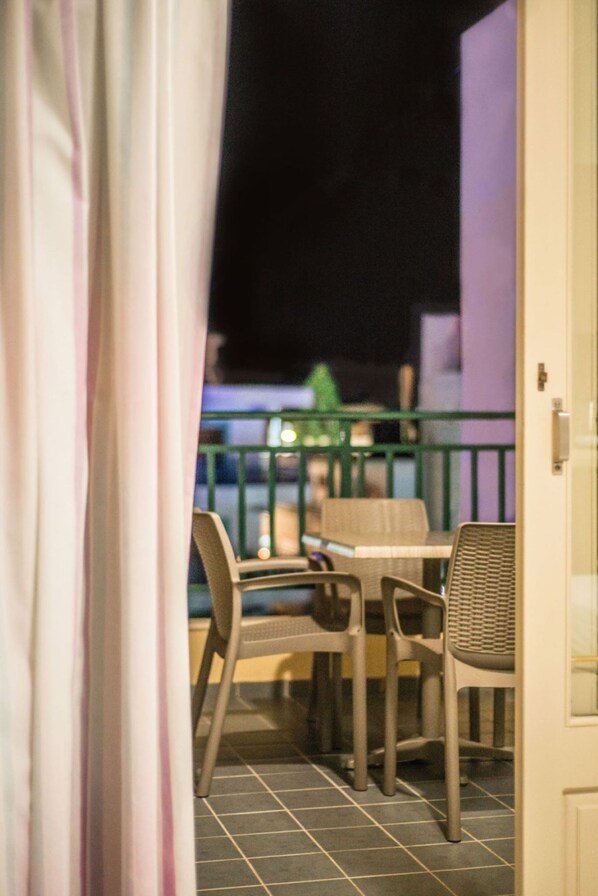 A balcony with outdoor seating, a railing, and a view of the night sky.