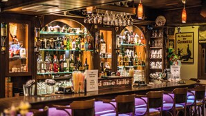 Een bar met flessen, glazen en een menukaart.