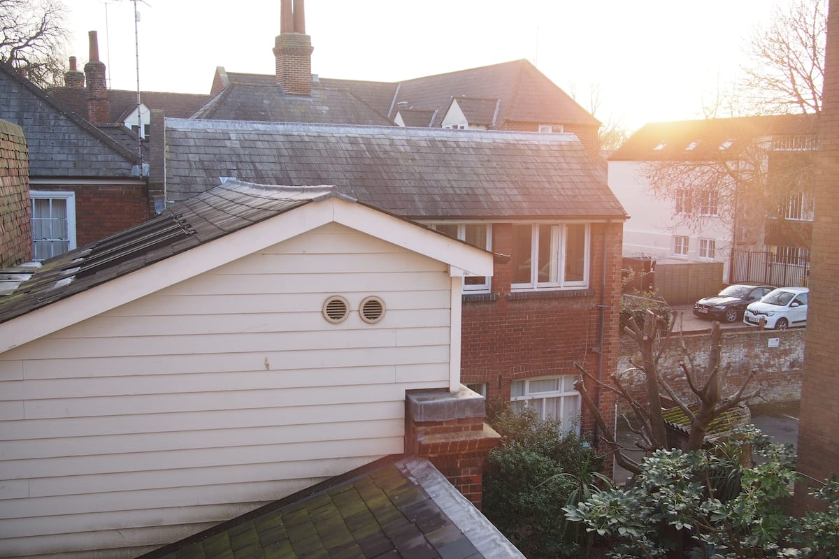 A residential building with a sloped roof, two chimneys, and a brick facade.