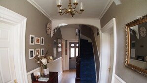 A hallway with a chandelier, a staircase, and a mirror on the wall. - The Coach House Canterbury (Canterbury)