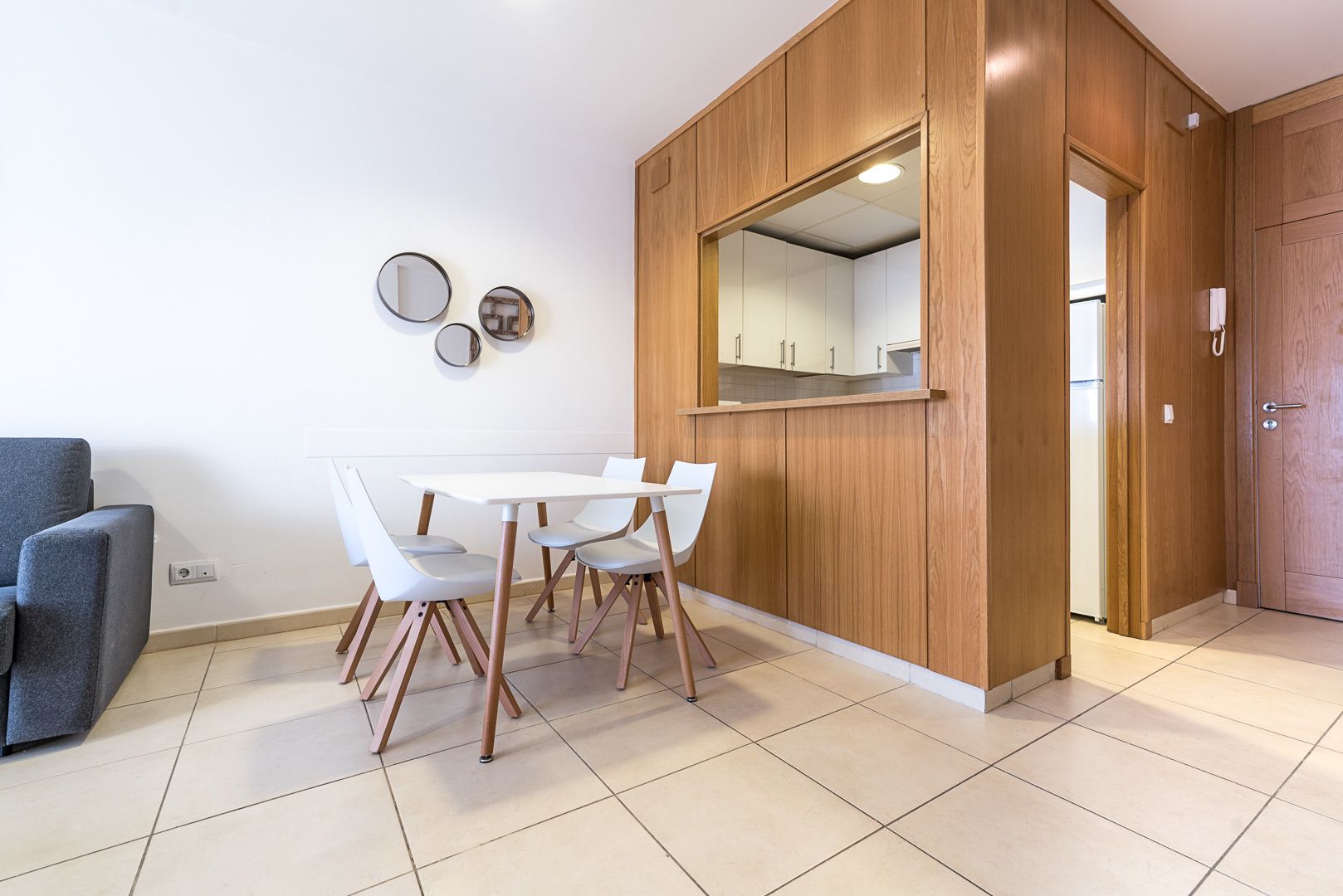 Een moderne keuken met houten kastjes en een grote spiegel boven het aanrecht.