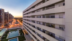 Un immeuble résidentiel à plusieurs étages, doté de balcons, d’une piscine et d’un espace paysager.