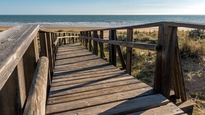 Une promenade en bois qui mène à une plage d’où l’on a une vue dégagée sur l’océan.